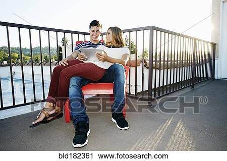 Stock Image - Couple using digital tablet on patio. Fotosearch
