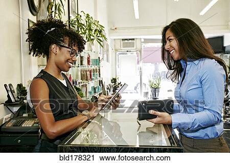 Customer paying hairstylist in salon View Large Photo Image Stock Image - Customer paying hairstylist in salon. Fotosearch