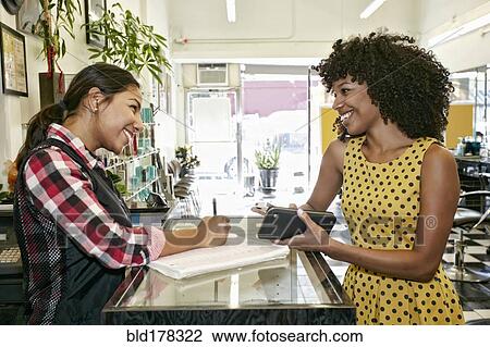 Customer paying hairstylist in salon View Large Photo Image Stock Image - Customer paying hairstylist in salon. Fotosearch