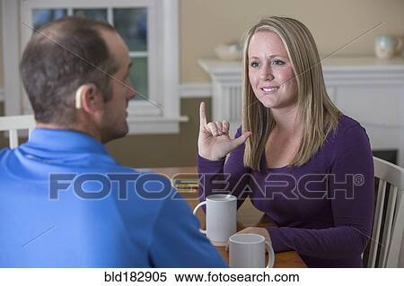 Stock Photography - Deaf Caucasian couple signing at dinner table. Fotosearch