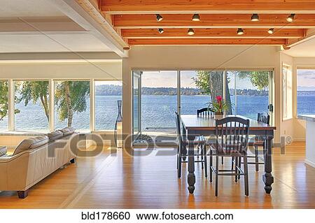 Stock Image - Dining table, sofa and glass walls in modern house. Fotosearch