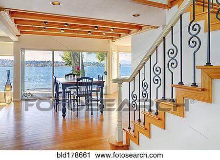 Stock Image - Dining table, staircase and glass walls in modern house. Fotosearch