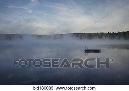 Stock Image - Dock floating on misty remote lake. Fotosearch