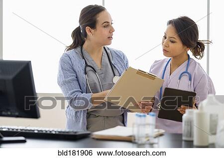Stock Photograph - Doctor and nurse talking in hospital. Fotosearch