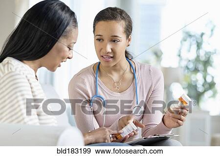 Stock Photo - Doctor and patient discussing medication in living room. Fotosearch