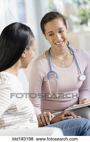 Stock Photo - Doctor comforting patient in living room. Fotosearch