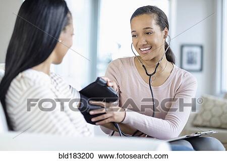 Doctor measuring blood pressure of patient in living room View Large Photo Image Stock Image - Doctor measuring blood pressure of patient in living room. Fotosearch
