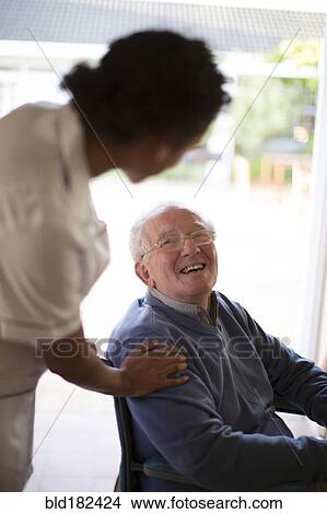 Picture - Doctor talking to patient in wheelchair. Fotosearch