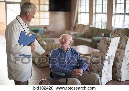 Stock Image - Doctor talking to patient in wheelchair. Fotosearch