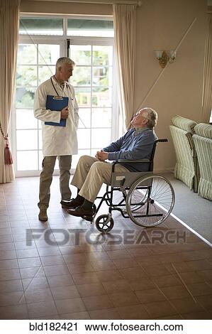 Stock Image - Doctor talking to patient in wheelchair. Fotosearch