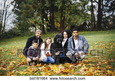 Picture - Family and dog smiling in park. Fotosearch