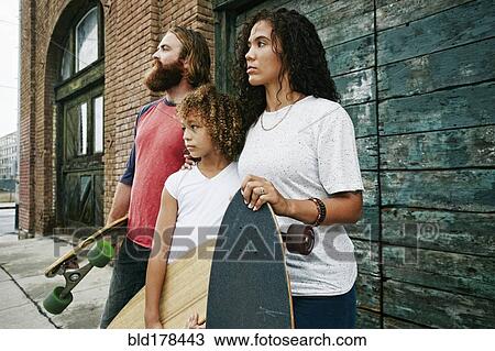 Stock Image - Family holding skateboards outdoors. Fotosearch