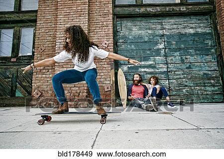 Stock Photo - Family riding skateboards on sidewalk. Fotosearch