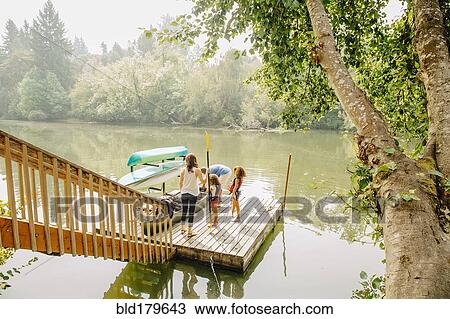 Stock Image - Family standing on dock in lake. Fotosearch