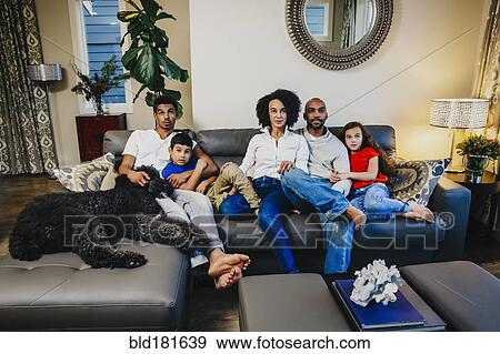 Stock Photo - Family watching television on sofa. Fotosearch