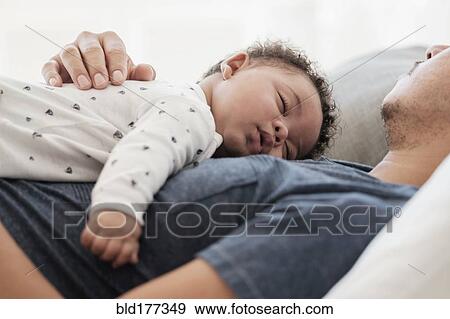Stock Photo - Father and baby son sleeping on bed. Fotosearch