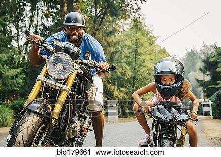 Stock Image - Father and daughter sitting on motorcycles. Fotosearch