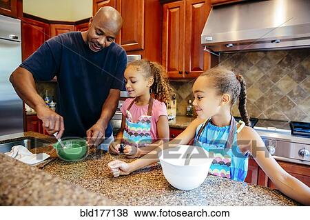 Stock Photo - Father and daughters cooking in kitchen. Fotosearch