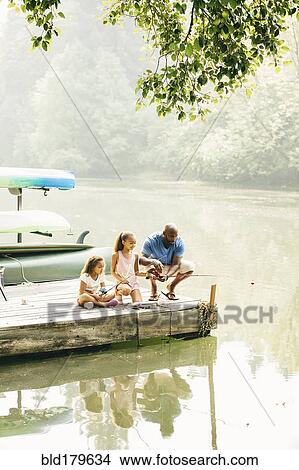 Picture - Father and daughters fishing in lake. Fotosearch