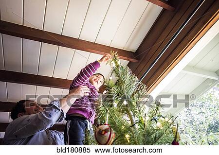 Stock Photography - Father and son decorating Christmas tree. Fotosearch