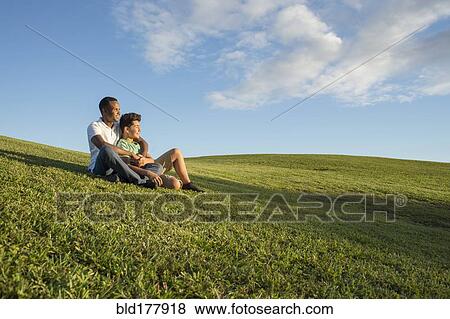 Stock Photo - Father and son sitting in grass. Fotosearch