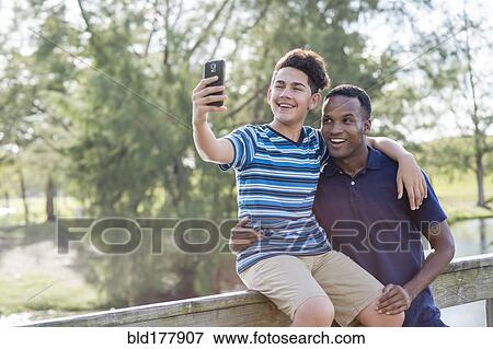 Stock Photo - Father and son taking selfie outdoors. Fotosearch