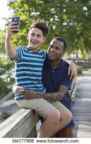 Stock Photo - Father and son taking selfie outdoors. Fotosearch
