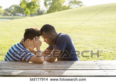 Father and son talking at table in park View Large Photo Image Picture - Father and son talking at table in park. Fotosearch