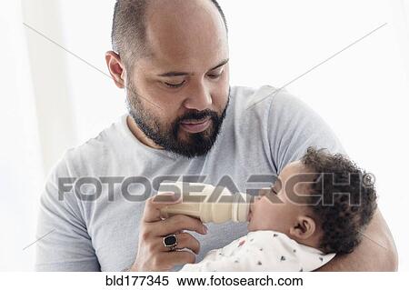 Stock Photography - Father bottle feeding baby son. Fotosearch