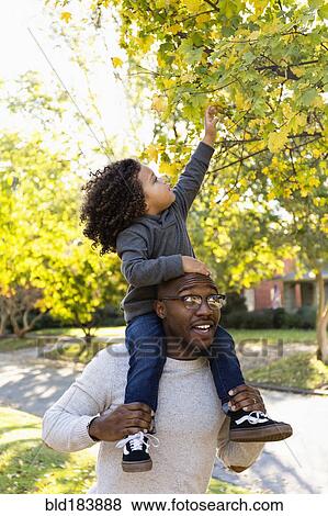 Father carrying son on shoulders outdoors View Large Photo Image Stock Photo - Father carrying son on shoulders outdoors. Fotosearch