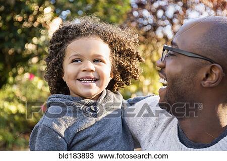 Stock Image - Father carrying son outdoors. Fotosearch