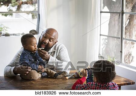 Father feeding baby son at table View Large Photo Image Stock Photograph - Father feeding baby son at table. Fotosearch