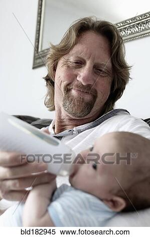Stock Photography - Father feeding baby son. Fotosearch