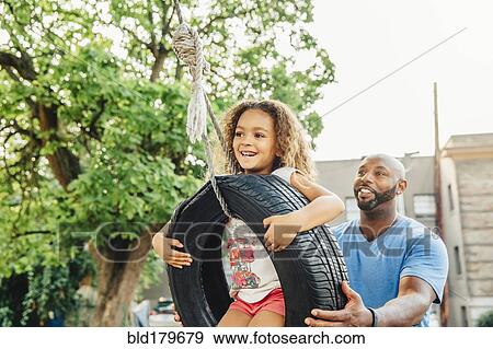 Father pushing daughter on tire swing View Large Photo Image Stock Photo - Father pushing daughter on tire swing. Fotosearch