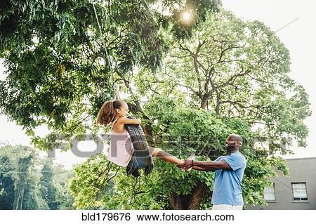 Father pushing daughter on tire swing View Large Photo Image Stock Photograph - Father pushing daughter on tire swing. Fotosearch