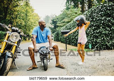 Father sitting on miniature motorcycle near daughter View Large Photo Image Stock Photo - Father sitting on miniature motorcycle near daughter. Fotosearch
