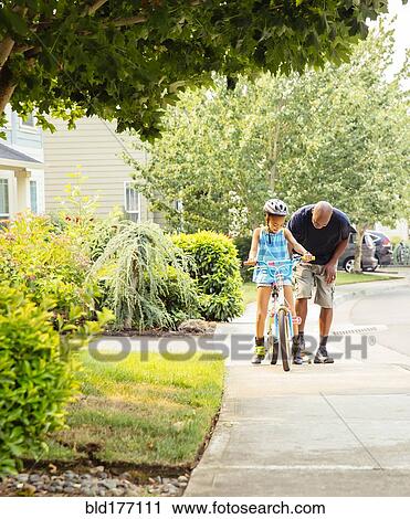 Father teaching daughter to ride bicycle View Large Photo Image Stock Image - Father teaching daughter to ride bicycle. Fotosearch