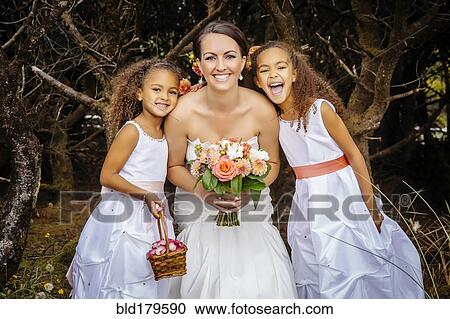 Stock Image - Flower girls smiling with bride outdoors. Fotosearch