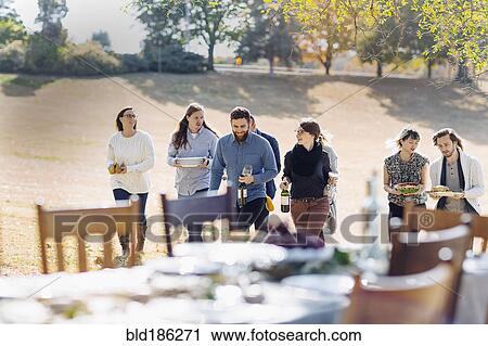 Friends carrying food to outdoor dining table View Large Photo Image Stock Image - Friends carrying food to outdoor dining table. Fotosearch