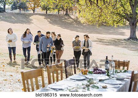 Friends carrying food to outdoor table in rural field View Large Photo Image Stock Photography - Friends carrying food to outdoor table in rural field. Fotosearch
