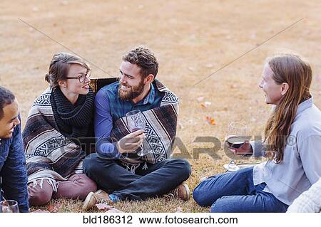Stock Image - Friends drinking wine in rural field. Fotosearch