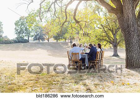 Stock Photograph - Friends eating at outdoor table. Fotosearch