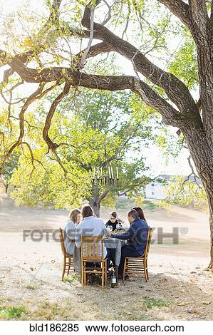Stock Photography - Friends eating at outdoor table. Fotosearch