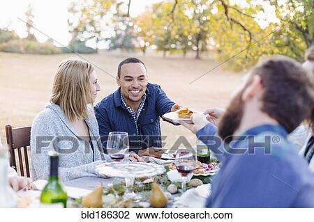 Stock Image - Friends eating pie at outdoor table. Fotosearch