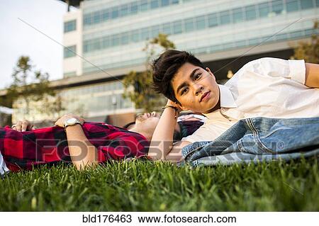 Stock Image - Friends laying in grass. Fotosearch