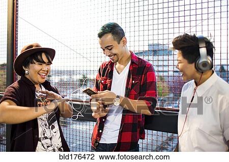 Stock Image - Friends listening to music outdoors. Fotosearch