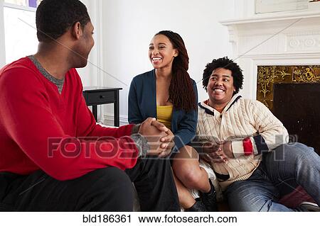 Friends relaxing in living room View Large Photo Image Stock Image - Friends relaxing in living room. Fotosearch