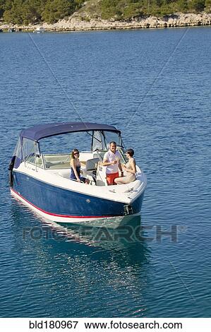 Stock Photo - Friends relaxing on boat in ocean. Fotosearch