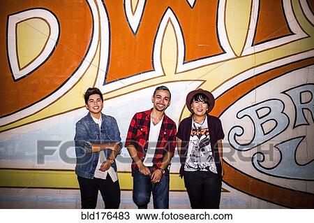 Stock Image - Friends smiling at mural outdoors. Fotosearch