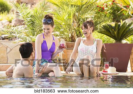 Stock Image - Friends talking in swimming pool. Fotosearch